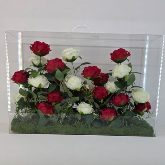 Artificial red and white flowers in a clear plastic container on a white background